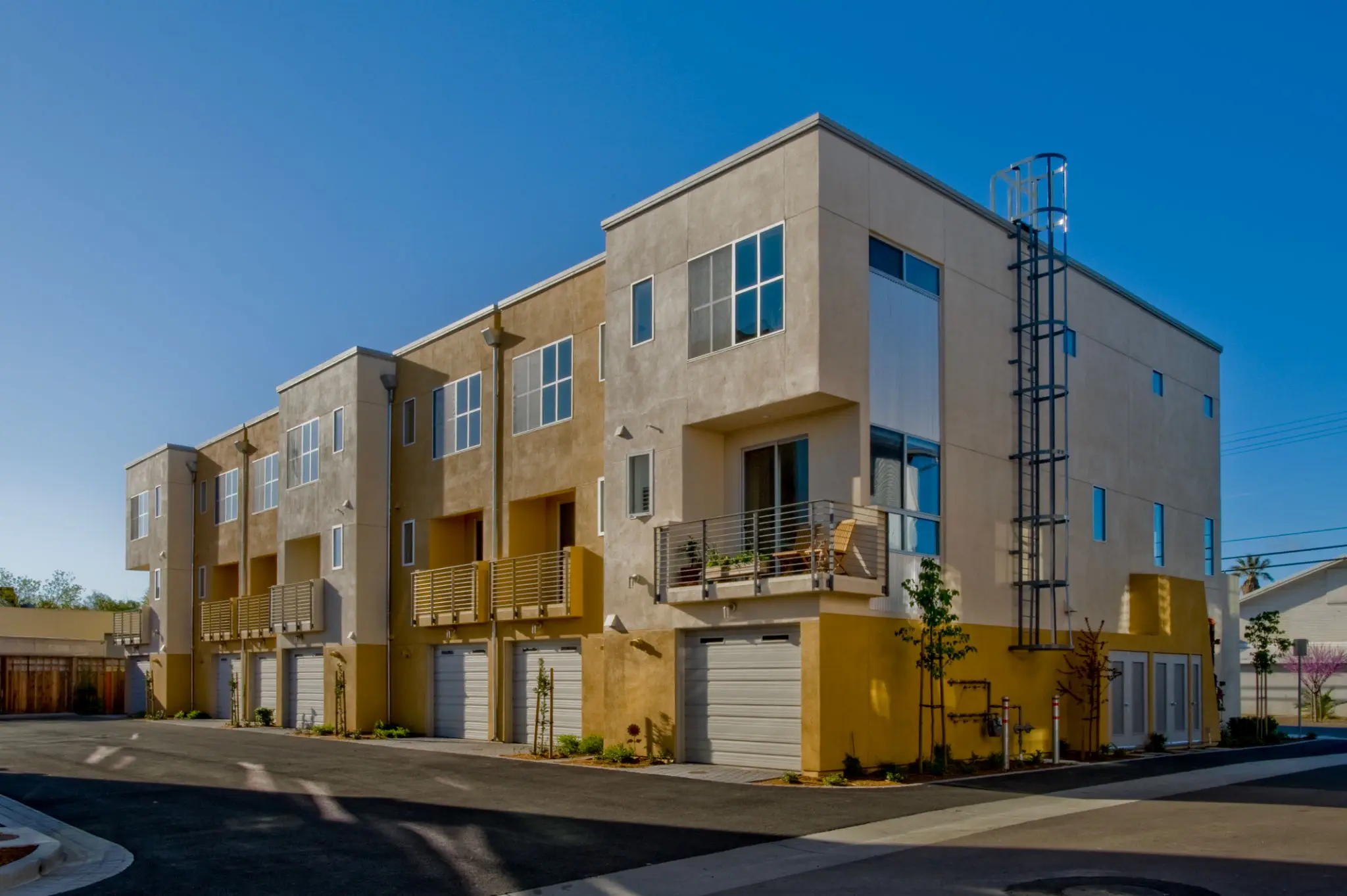 Modern beige apartment complex under clear blue sky.
