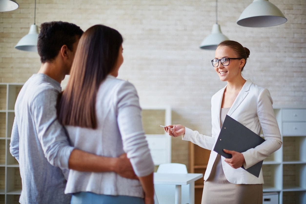 A professional woman presenting a house to a couple in a modern setting.