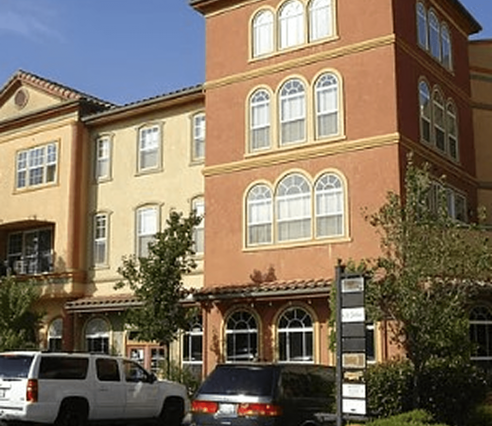 Charming multi-story residential building with warm-colored facade and arched windows.