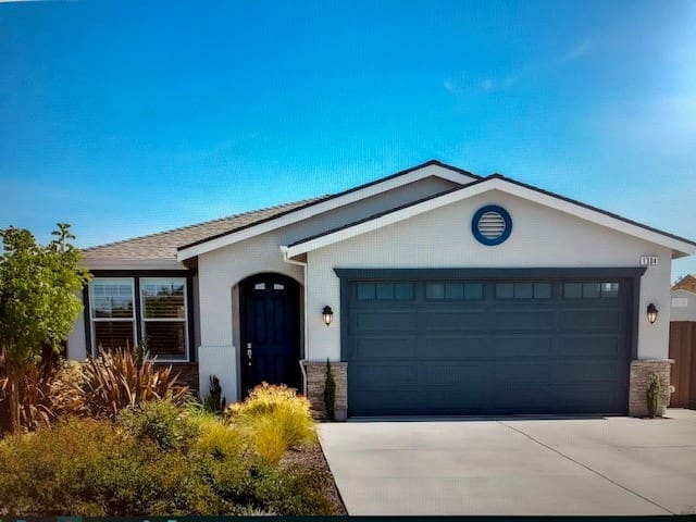Modern single-story house with a two-car garage and landscaped front yard.